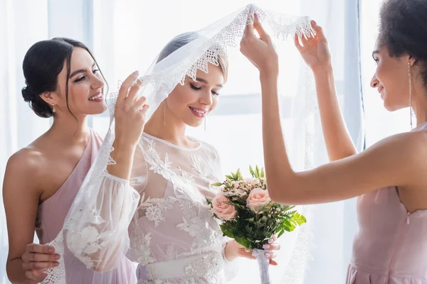 Mulher afro-americana levantando véu de noiva segurando buquê de casamento — Fotografia de Stock