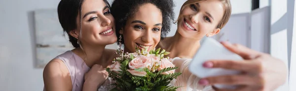 Happy african american woman taking selfie with wedding bouquet and friends, blurred foreground, banner — Stock Photo