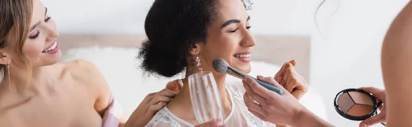 Bridesmaid applying highlighter on face of african american bride, banner — Stock Photo
