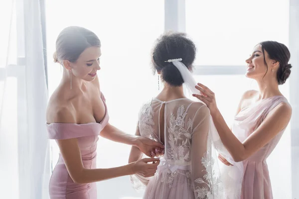 Pretty bridesmaids dressing african american woman for wedding — Stock Photo