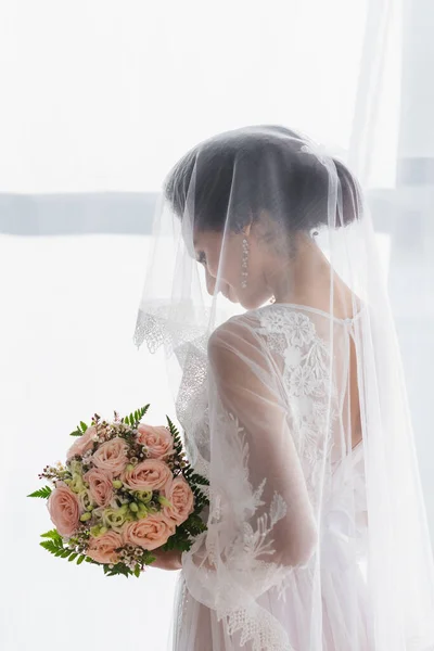 Afrikanisch-amerikanische Braut in Schleier hält Brautstrauß zu Hause — Stockfoto
