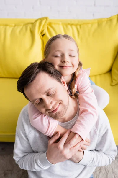Щаслива дівчина обіймає батька закритими очима вдома — стокове фото