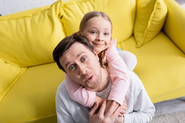 Vue grand angle de fille gaie et père grimaçant regardant la caméra — Photo de stock