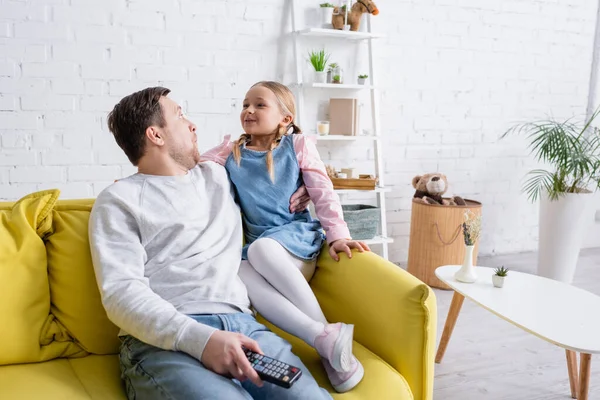 Erstaunt schauen Vater und Tochter einander an, während sie sich zu Hause einen Film ansehen — Stockfoto