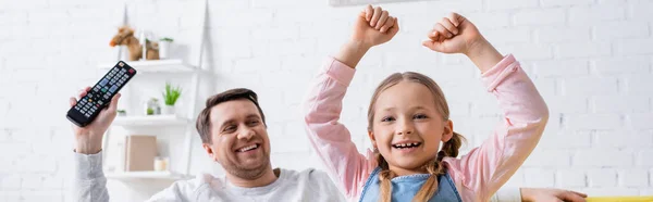 Cheerful man holding remote controller near child showing win gesture, banner — Stock Photo