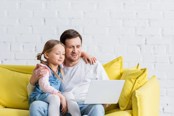 Homme étreignant fille tout en regardant le film sur ordinateur portable à la maison — Photo de stock