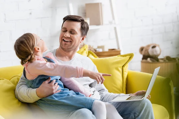 Girl pointing with finger while watching movie on laptop with father — Stock Photo