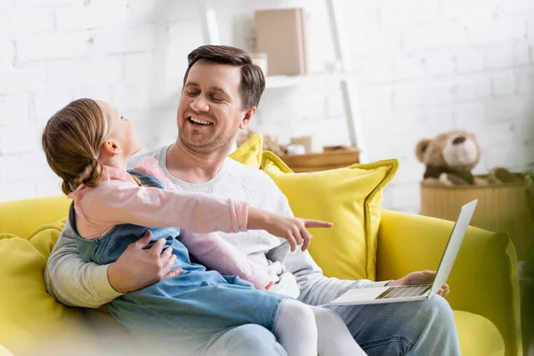 Chica señalando con el dedo mientras mira la película en el ordenador portátil con el padre — Stock Photo