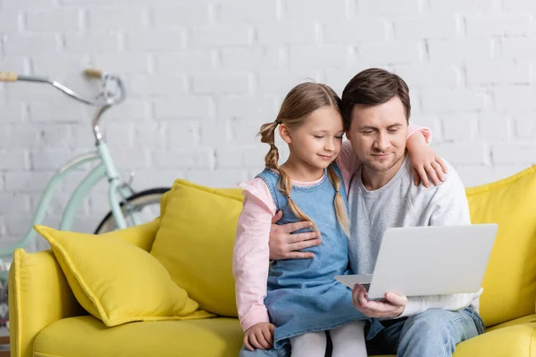 Padre sorridente e bambino guardando film sul computer portatile a casa — Foto stock