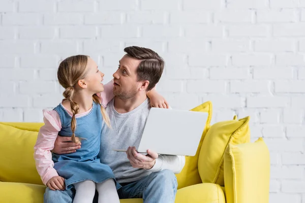 Amazed father and daughter looking at each other while watching movie on laptop — Stock Photo