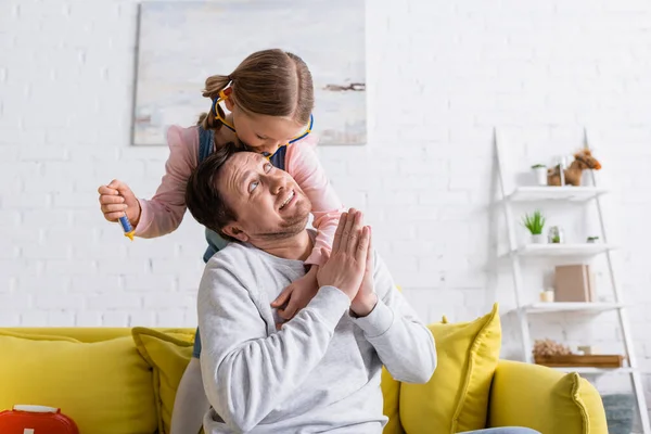 Mann zeigt bitte Geste nahe Tochter mit Spielzeugspritze — Stockfoto