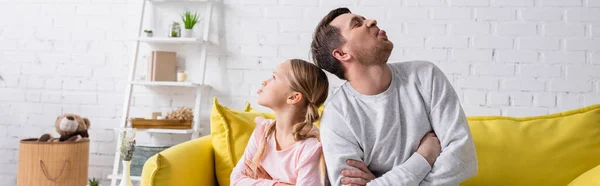 Ofendido papá e hija sentado espalda con espalda y sobresaliendo lenguas, pancarta - foto de stock