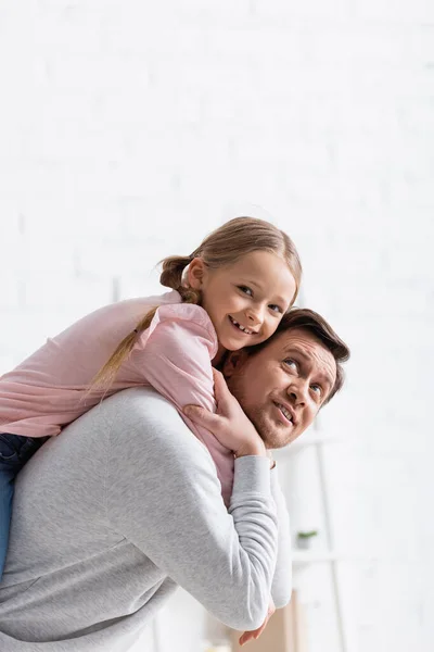 Sorridente uomo cavalcando figlia felice a casa — Foto stock