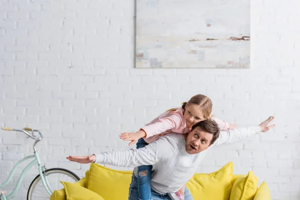 Pai e filha mostrando gesto de mosca enquanto se divertindo em casa — Fotografia de Stock