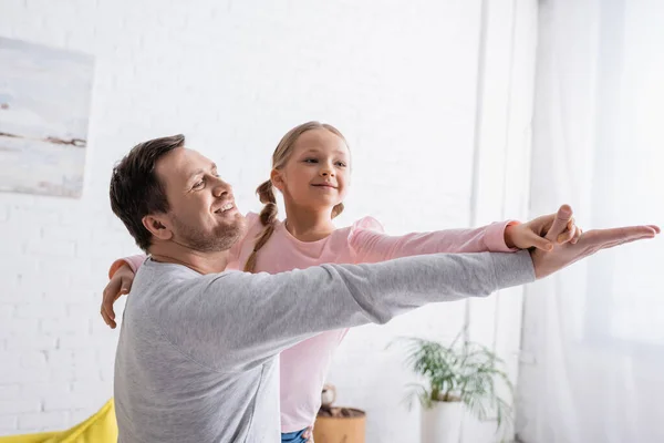 Alegre padre e hija tomados de la mano mientras bailan en casa - foto de stock