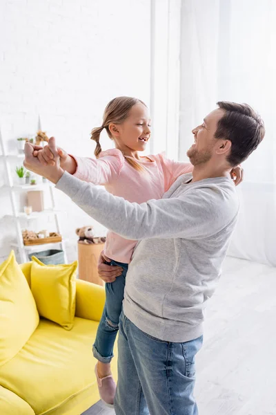 Glücklicher Mann hält Tochter und tanzt zu Hause — Stockfoto