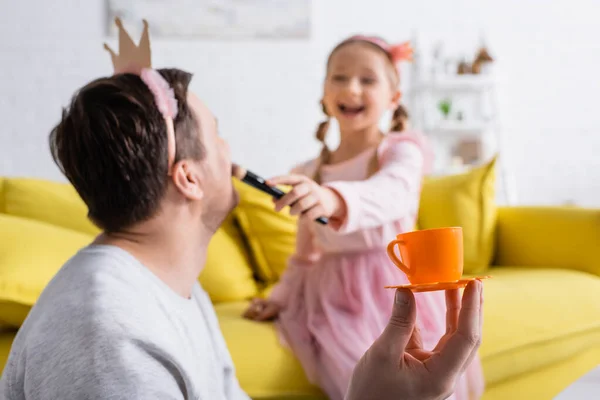 Ragazza eccitata facendo trucco al padre indossando corona giocattolo, sfondo sfocato — Foto stock