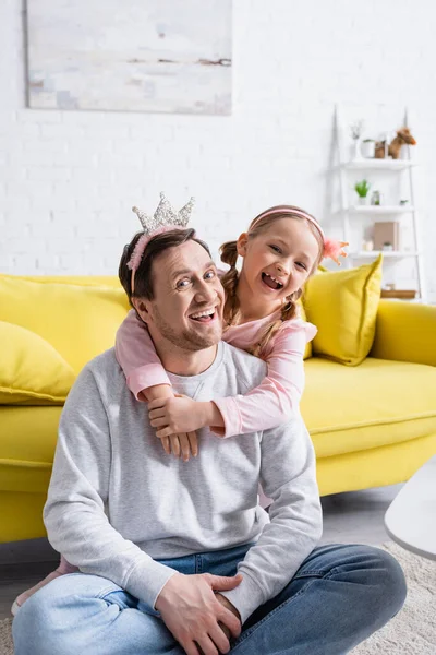 Ragazza eccitata abbracciando padre felice mentre gioca principe e principessa a casa — Foto stock