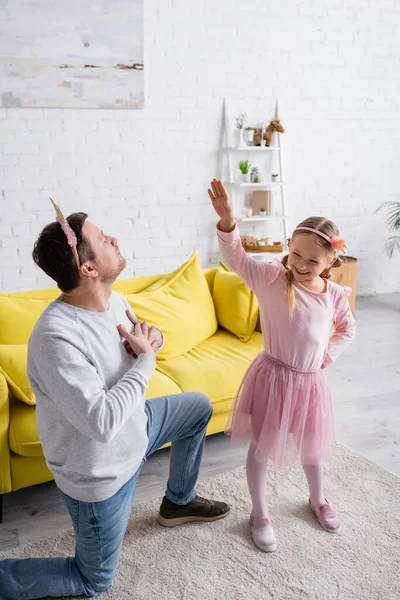 Батько в іграшковій короні стоїть на коліні і запрошує дочку танцювати — стокове фото