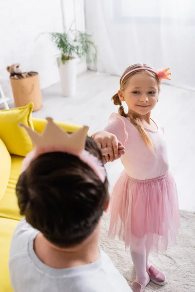 Chica en juguete corona bailando con padre en borrosa primer plano - foto de stock