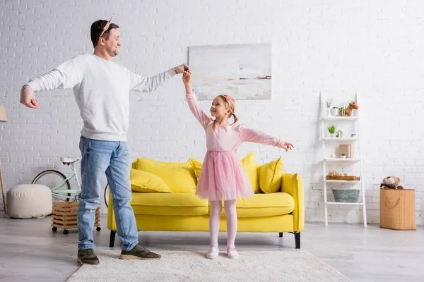 Glücklicher Vater und Tochter in Spielzeugkronen tanzen zu Hause — Stockfoto