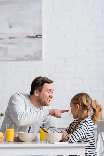 Fröhlicher Vater zeigt beim Frühstück auf Tochter — Stockfoto