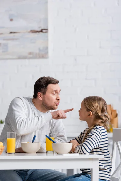 Father pointing at nose of daughter while having fun during breakfast — Stock Photo