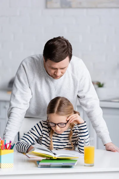 Мужчина рядом с дочерью делает домашнее задание на кухне — стоковое фото