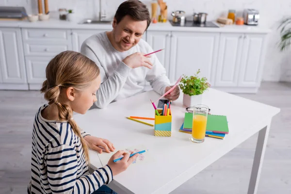 Feliz padre e hija dibujo con lápices de color en la cocina - foto de stock