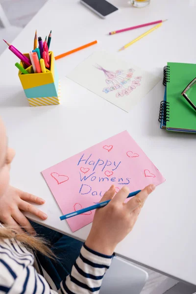 Vue recadrée de l'enfant dessinant la carte heureuse de jour de femmes sur le premier plan flou — Photo de stock