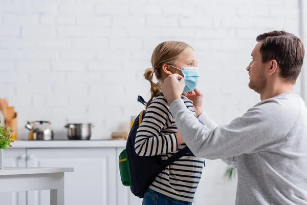Mann setzt Tochter mit Rucksack Schutzmaske auf — Stockfoto