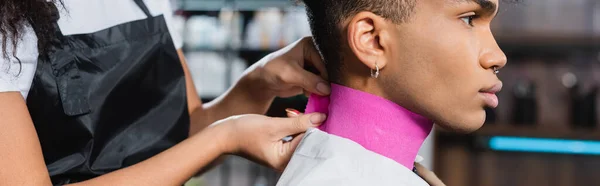 Parrucchiere afroamericano che indossa carta collare sul cliente, banner — Foto stock