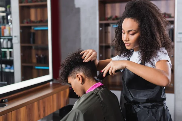 Африканський американець перукаря стриже шию клієнта в плащ і комір паперу — стокове фото