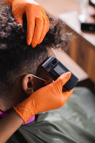 Coiffeur afro-américain en gants de latex coupe les cheveux de l'homme — Photo de stock
