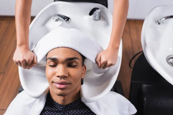 Top view of african american client sitting near hairstylist with towel and sink — Stock Photo