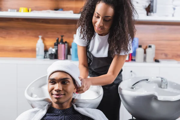 African american hairstylist drying hair of smiling man with towel — Stock Photo