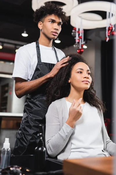 Mujer afroamericana mostrando longitud a peluquero en salón - foto de stock