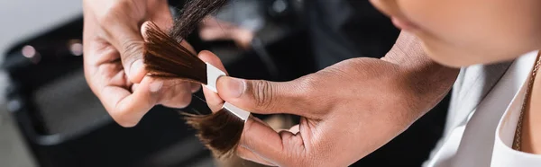 Cropped view of african american hairdresser holding color samples near client, banner — Stock Photo