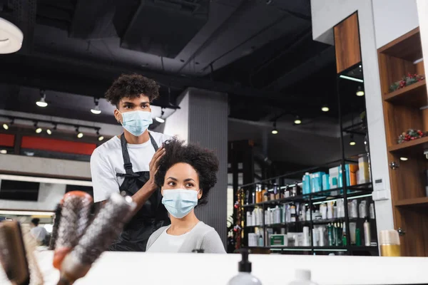 Coiffeur afro-américain toucher les cheveux de la femme dans le masque médical — Photo de stock