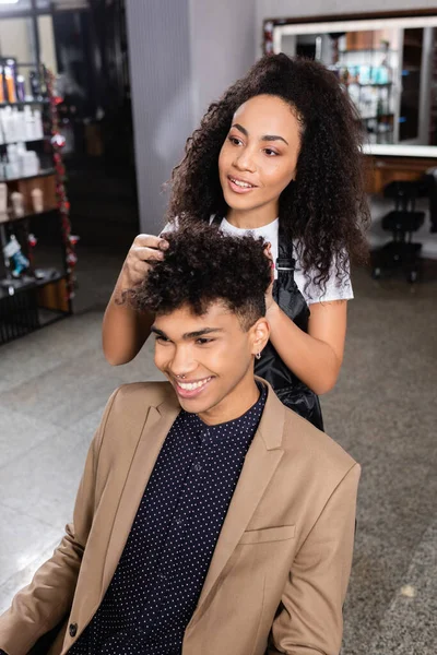 Sorrindo Africano americano cabeleireiro trabalhando com jovem cliente — Fotografia de Stock
