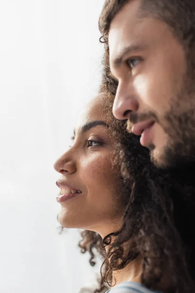 Feliz africano americano mujer sonriendo cerca novio en borrosa primer plano - foto de stock