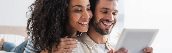 Couple multiethnique joyeux regardant tablette numérique, bannière — Photo de stock