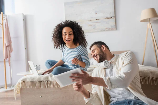 Couple multiethnique regardant tablette numérique dans la chambre — Photo de stock