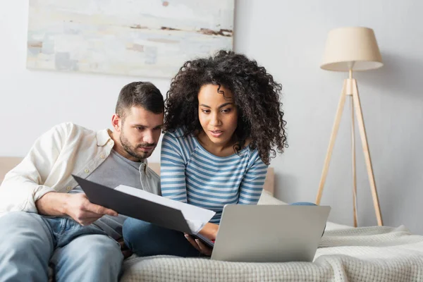 Casal interracial olhando para laptop no quarto — Fotografia de Stock