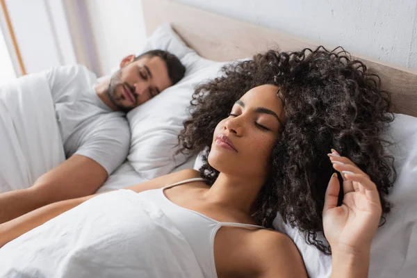 Curly african american woman sleeping near boyfriend on blurred background — Stock Photo