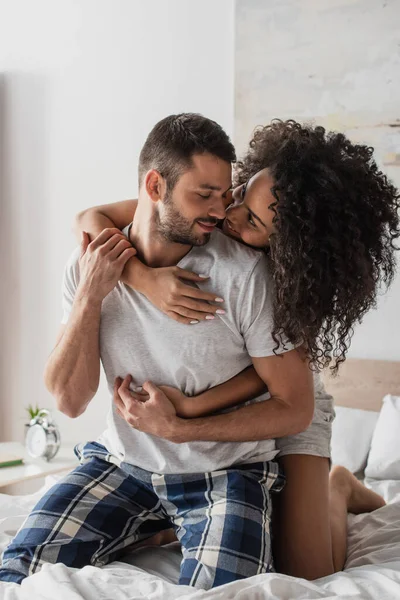 Rizado africano americano mujer abrazando alegre novio en dormitorio - foto de stock