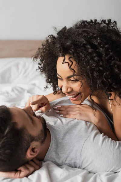 Positive interracial paar liegend zusammen auf bett — Stockfoto