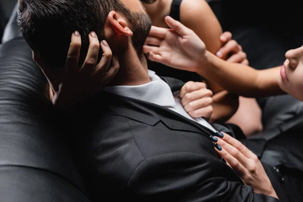 Abgeschnittene Ansicht leidenschaftlicher Frauen verführt Geschäftsmann auf verschwommenem Hintergrund isoliert auf schwarz — Stockfoto
