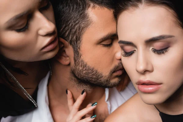 Sensual women with closed eyes seducing young man on blurred foreground — Stock Photo