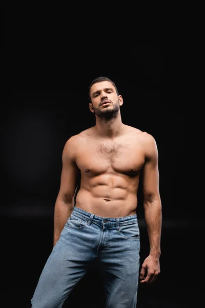 Sexy homem com muscular torso olhando para a câmera no fundo preto — Fotografia de Stock